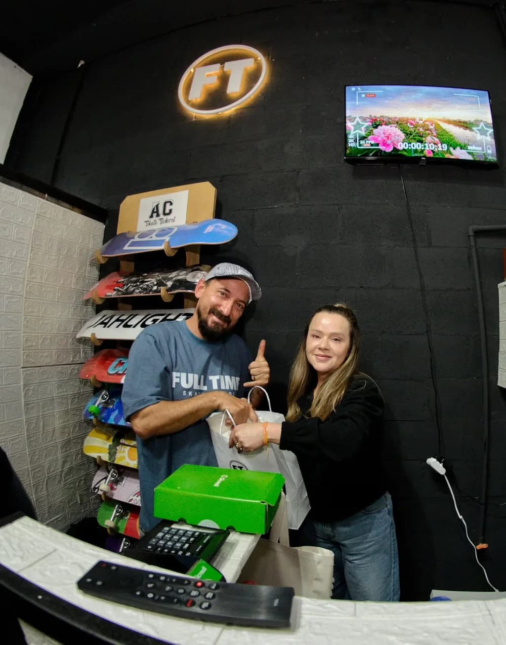 Anderson Camargo no balcão da loja, entregando a sacola a uma cliente